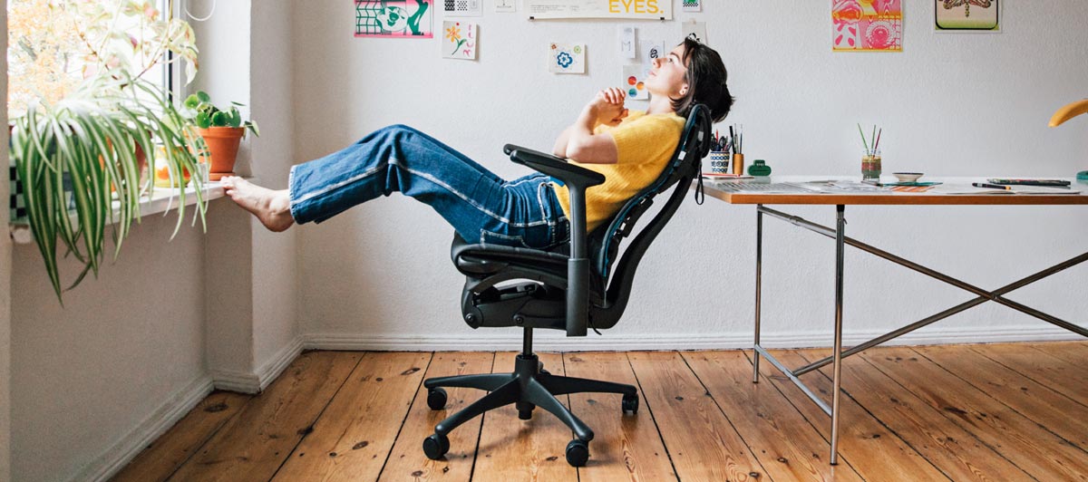 Illustrator, maler og forfatter Molly Rose Dyson i sit atelier, hvor hun sad tilbagelænet i en Embody-gamingstol i sort og cyanblå