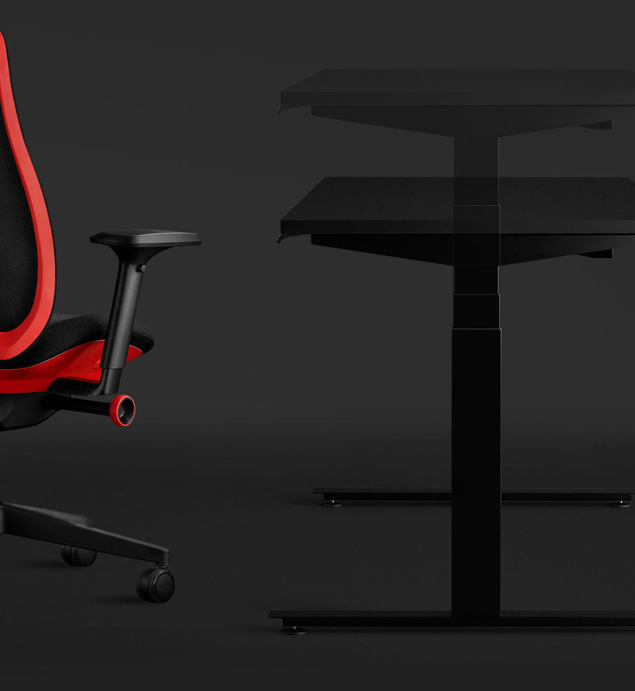 Sidebillede af et sort Nevi-gamingbord og en rød Vantum-gamingstol fra Herman Miller, der fremhæver skrivebordets hæve-sænke-element.