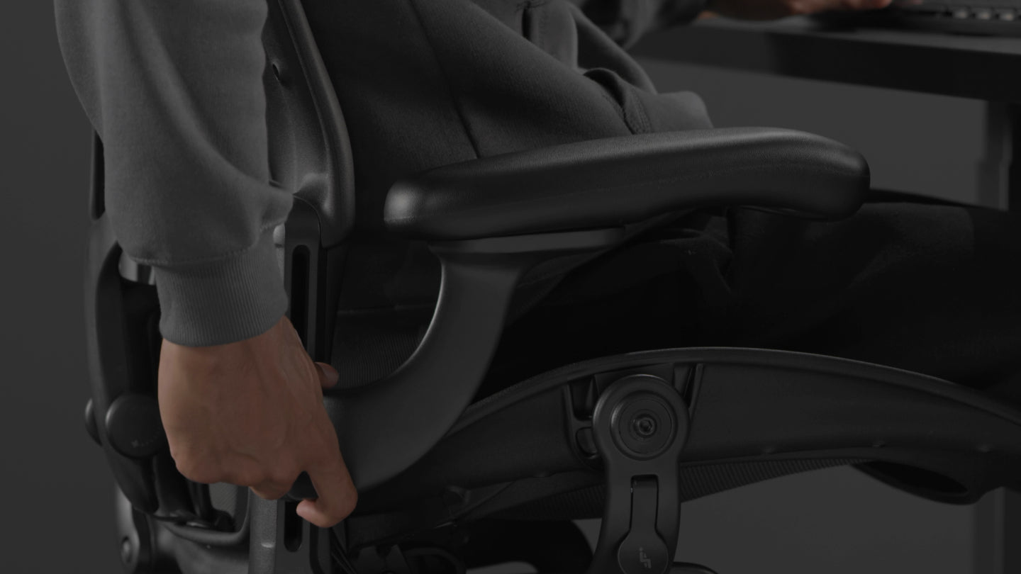 En video af en person, der sidder i en sort Aeron-gamingstol fra Herman Miller og rækker ud ved siden af stolen for at justere armene.