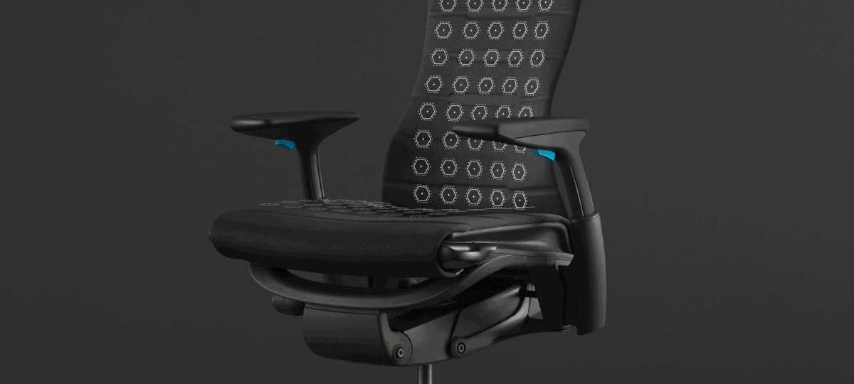 Skriftbillede af en sort og blå Embody-gamingstol fra Herman Miller, overlejret med hvid grafik, der fremhæver sæde og ryg.