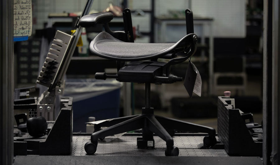 Base og sæde på en sort Aeron-gamingstol fra Herman Miller i fabriksindstilling.