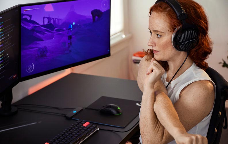 Esports-læge Lindsey Migliore foran gaming-opsætning med dobbelte skærme på Ollin-skærmarme