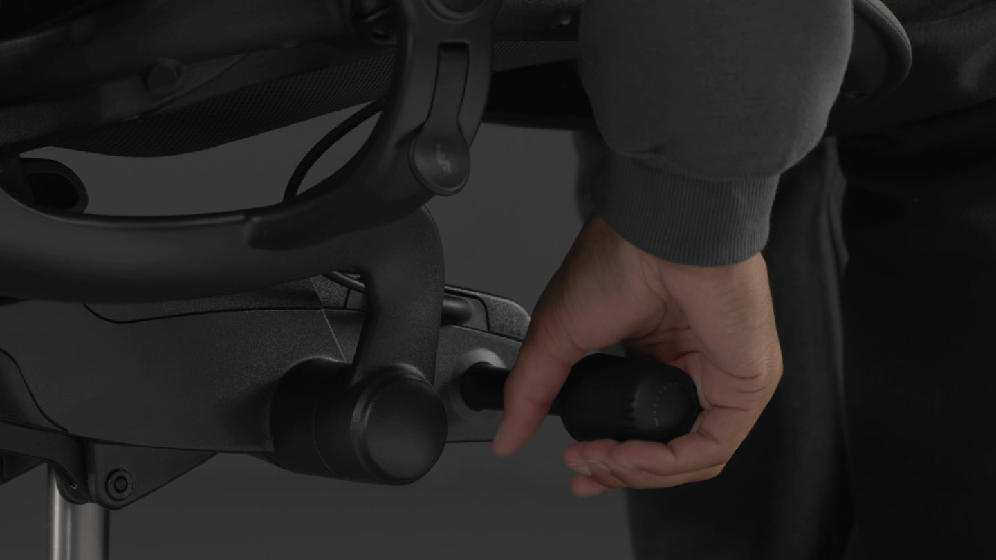 En video af en person, der sidder i en sort Aeron-gamingstol fra Herman Miller og rækker ud efter stolen for at justere vippespændingen.