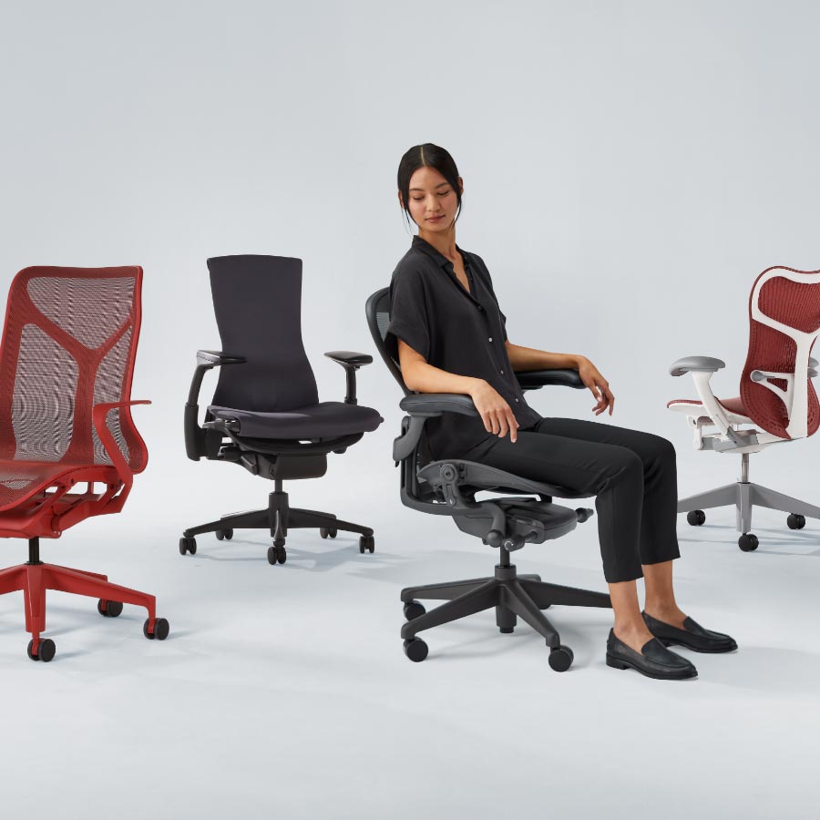 Fire Herman Miller-kontorstole, herunder Cosm med mellemhøj ryg i canyonrød, Embody i sort, Aeron i grafit med dame siddende og endelig Mirra 2 med hvid ramme og rødt sæde og ryglæn