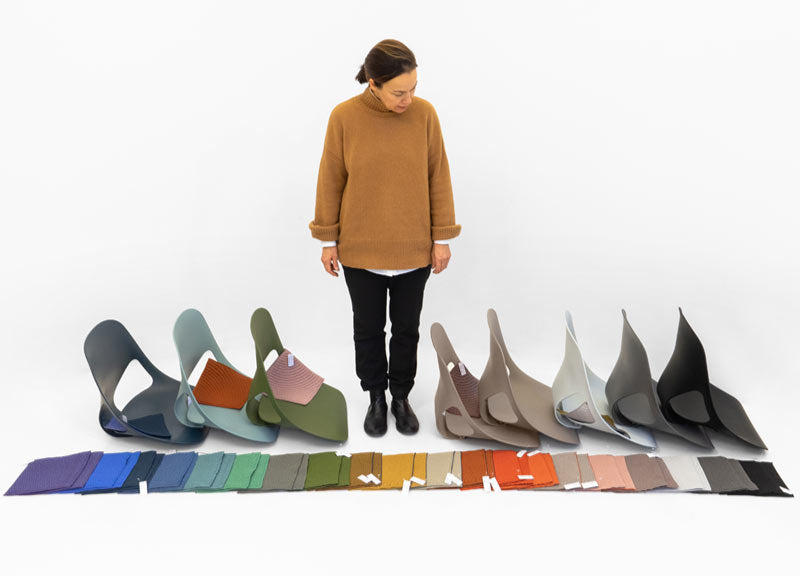 Designer fra Studio 7.5 kigger ned på gulvet på materialevalg og Zeph-sæder i forskellige farver