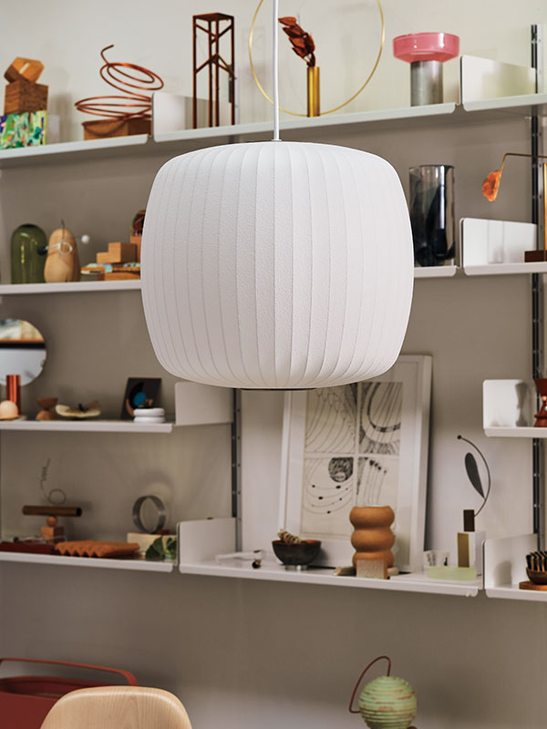 Nærbillede af Roll Nelson Bubble-loftslampe hængende foran hylder fyldt med ikoniske ornamenter