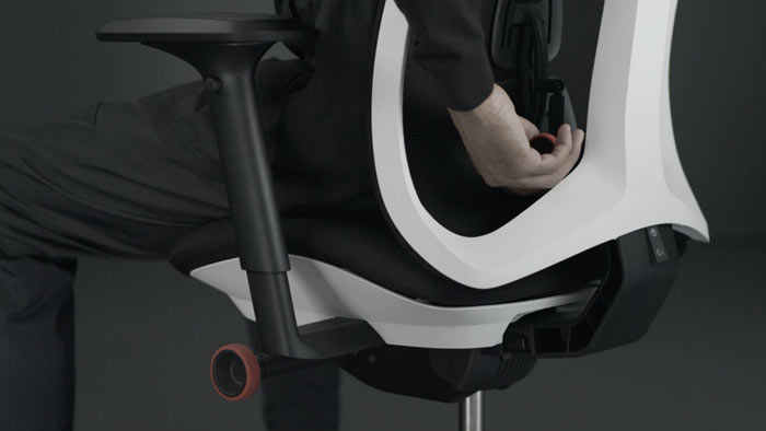 En video af en person, der sidder i en hvid og sort Vantum-gamingstol fra Herman Miller og rækker om bag stolen for at justere rygstøtten.