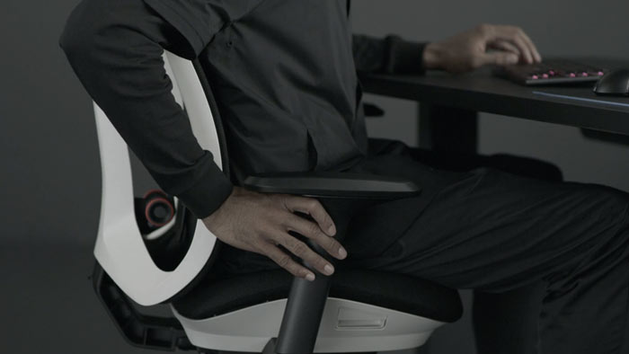 En video af en person, der sidder i en hvid og sort Vantum-gamingstol fra Herman Miller, og rækker ud ved siden af stolen for at justere armene.
