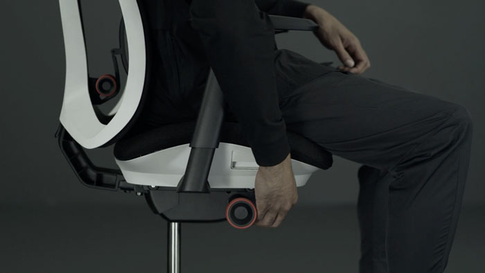 En video af en person, der sidder i en hvid og sort Vantum-gamingstol fra Herman Miller og rækker ud ved siden af stolen for at justere sædehøjden.