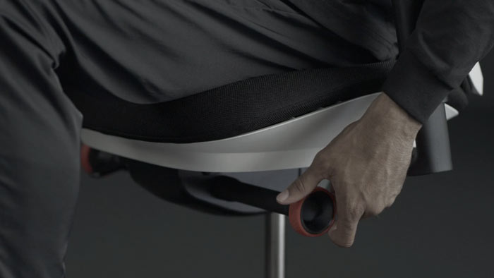 En video af en person, der sidder i en hvid og sort Vantum-gamingstol fra Herman Miller og rækker ud efter stolen for at justere vippebegrænseren.