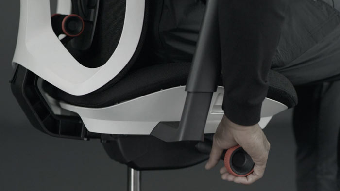En video af en person, der sidder i en hvid og sort Vantum-gamingstol fra Herman Miller, og rækker ud efter stolen for at justere vippespændingen.
