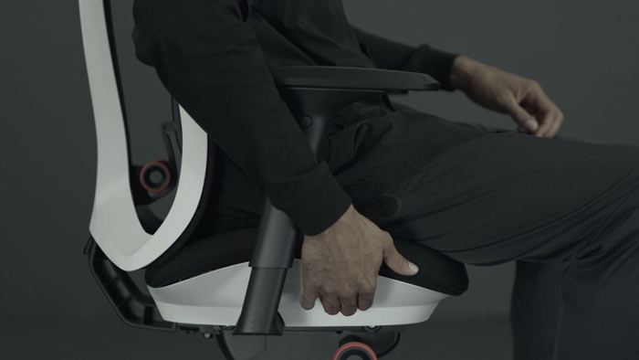 En video af en person, der sidder i en hvid og sort Vantum-gamingstol fra Herman Miller og rækker ud efter stolen for at justere sædedybden.