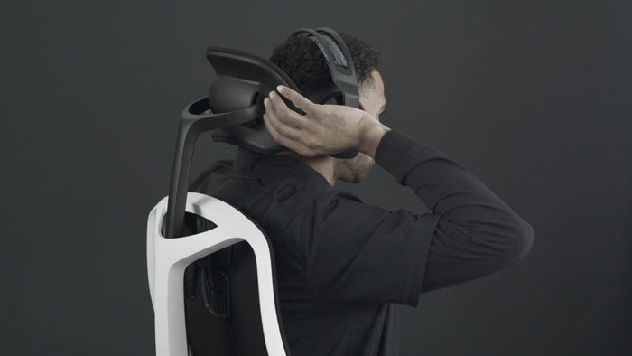 En video af en person, der sidder i en hvid og sort Vantum-gamingstol fra Herman Miller og rækker om bag stolen for at justere nakkestøtten.