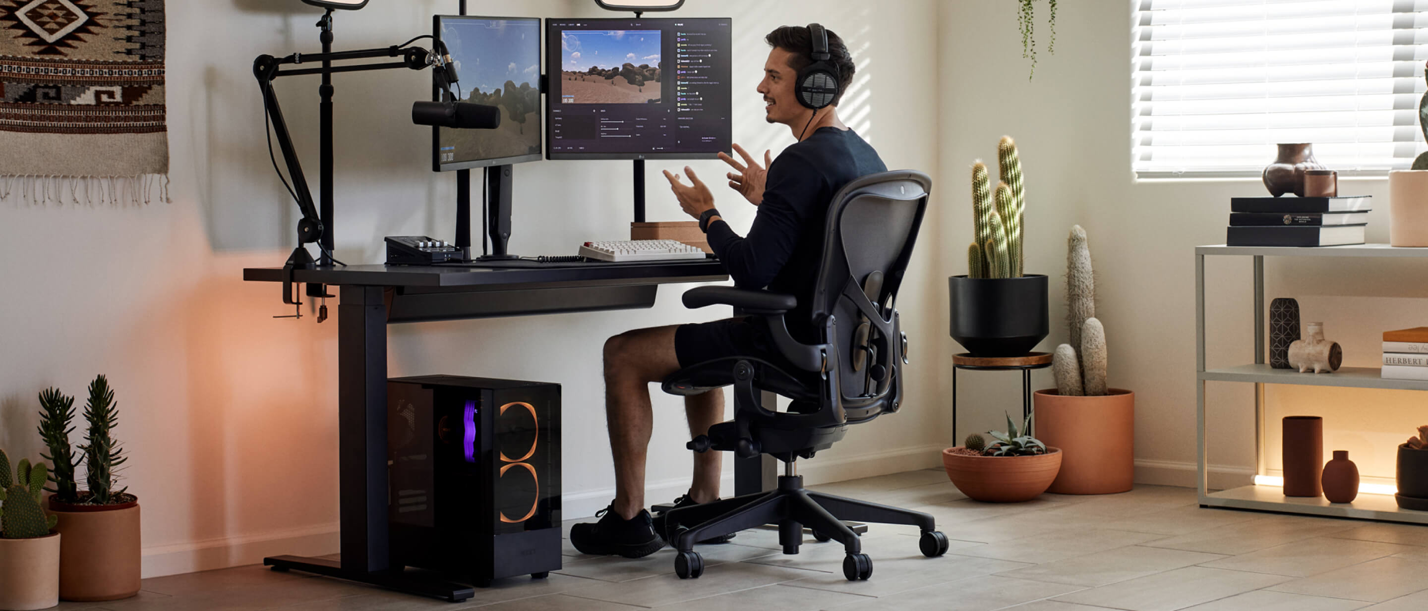 Gamer Xaryu med hænderne i vejret, mens han spiller på sit Herman Miller-setup i Aeron-gamingstol med Nevi-gamingbord og Ollin-dobbeltmonitorarme