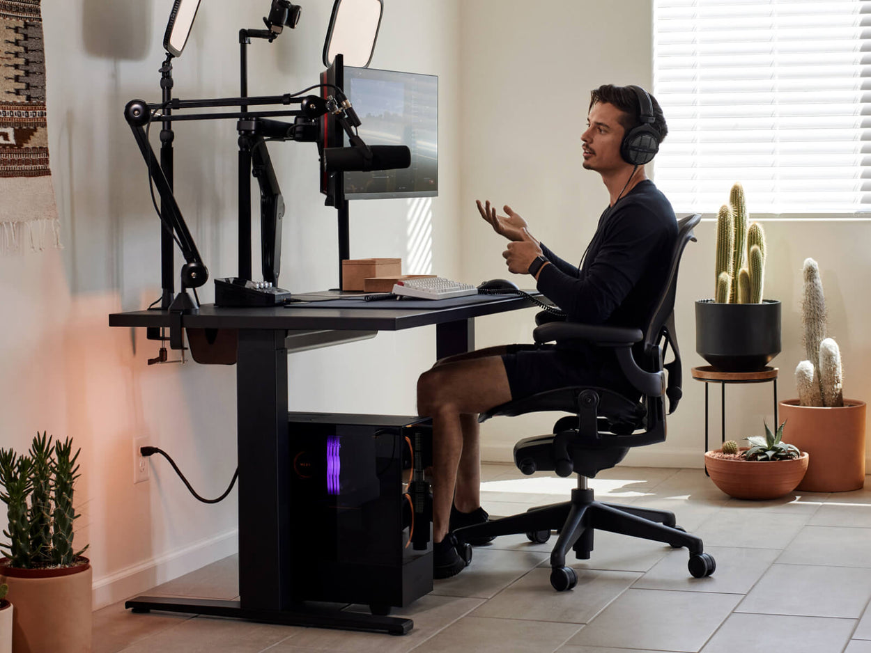 Gamer Xaryu sidder ved sit gaming-setup med en Aeron gaming-stol i grafit med Nevi gaming-bord og Ollin dobbelte monitorarme