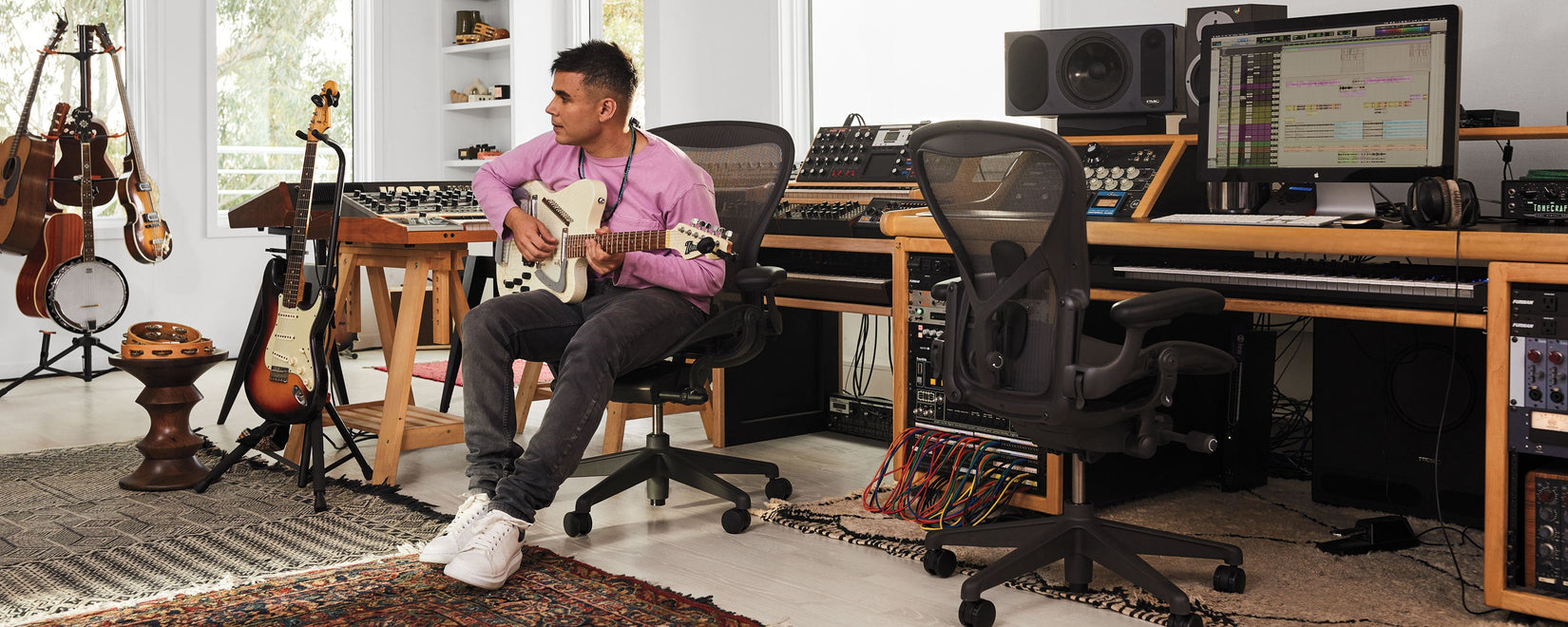 Rostam Batmanglij, musiker, producer og komponist, i sit musikstudie, hvor han spiller på en Italia Modena Electric Sitar-guitar, siddende i en Aeron-kontorstol i grafit.